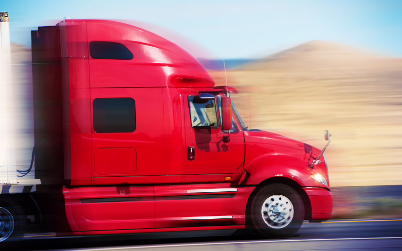 Red semi truck and trailer driving on a highway